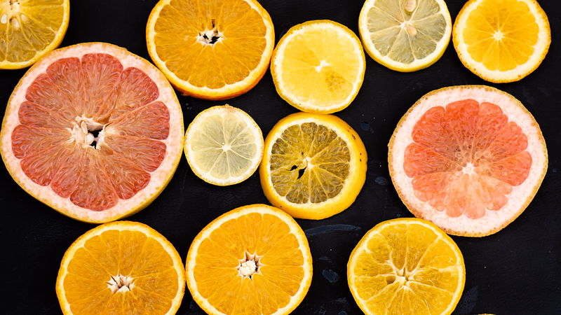Tranches d’oranges, de citrons et de pamplemousses disposées sur fond sombre